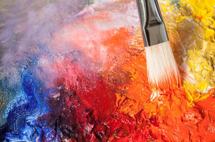 image of an artists brush on a mixed paint colours palette