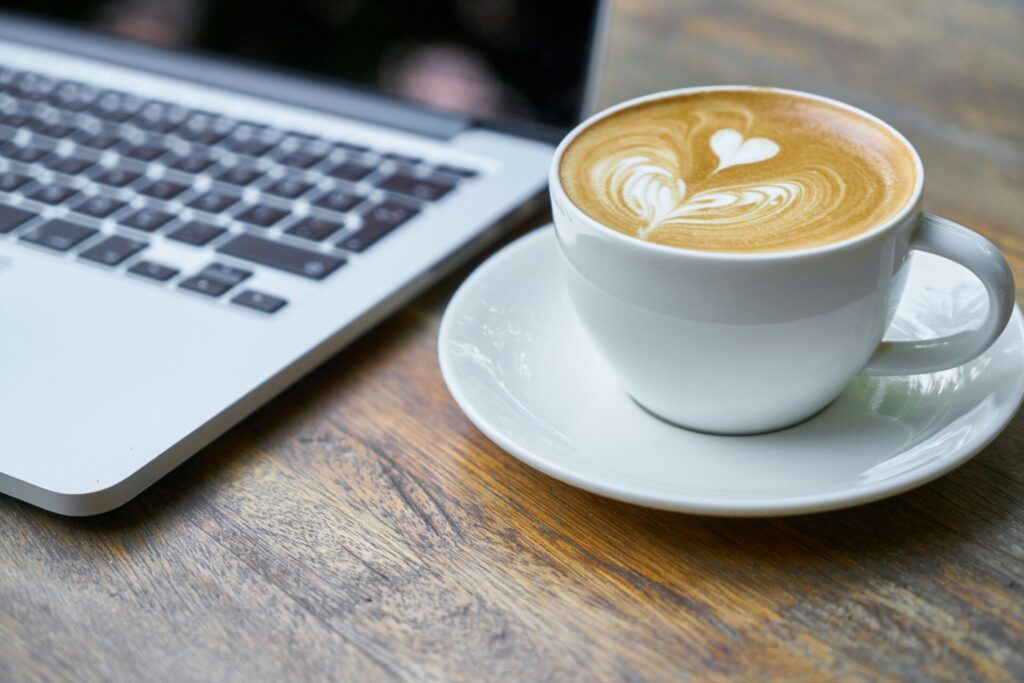 image of a cup of coffee next to a laptop